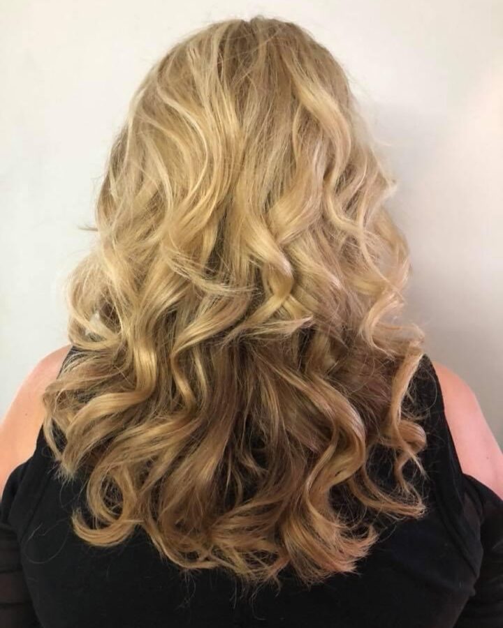 the back of a blonde woman with long wavy hair
